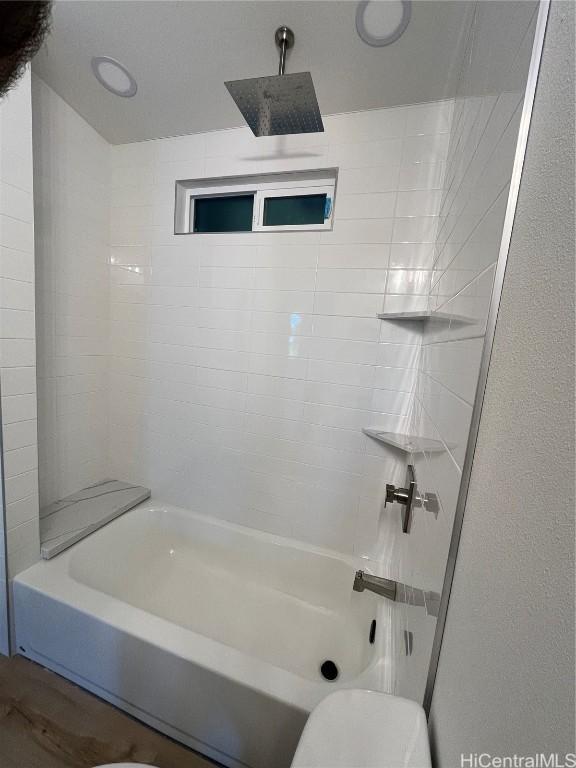 bathroom featuring washtub / shower combination, toilet, and hardwood / wood-style floors