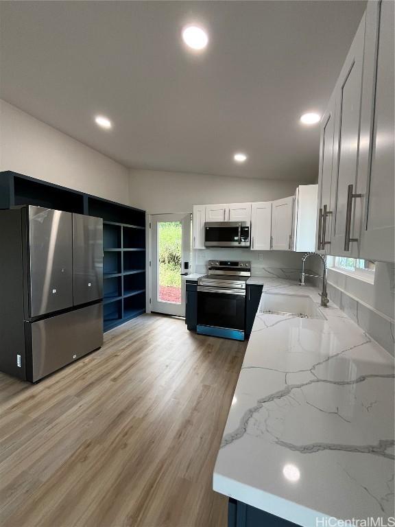 kitchen featuring sink, light hardwood / wood-style flooring, stainless steel appliances, light stone countertops, and white cabinets