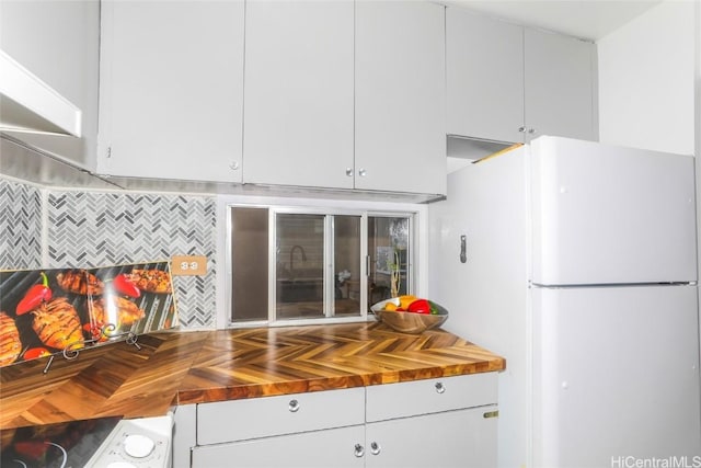 kitchen featuring parquet flooring, wood counters, white cabinetry, washer / dryer, and white fridge