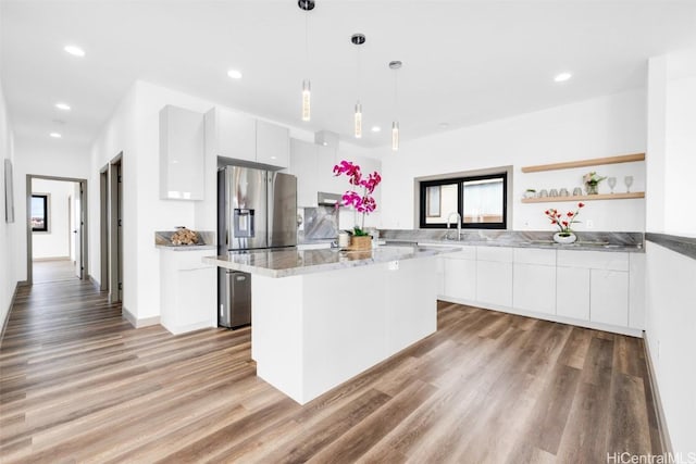 kitchen with sink, white cabinetry, hanging light fixtures, light hardwood / wood-style flooring, and a kitchen island