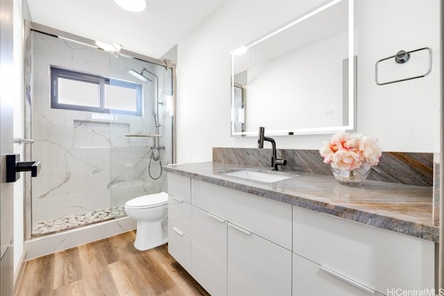 bathroom featuring vanity, hardwood / wood-style flooring, a shower with door, and toilet