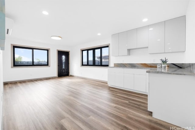 kitchen with light stone countertops, white cabinets, and light wood-type flooring