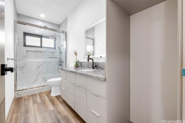 bathroom featuring hardwood / wood-style flooring, vanity, toilet, and a shower with shower door