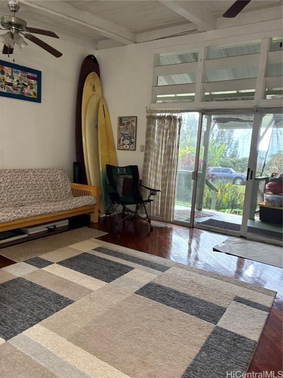 sitting room with a ceiling fan, beam ceiling, and dark wood finished floors