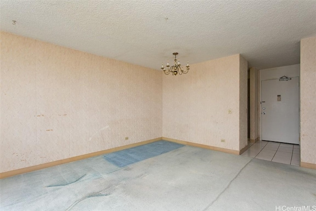 spare room featuring a textured ceiling and a notable chandelier