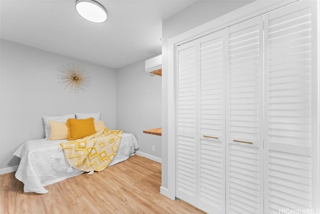 bedroom featuring a closet, light hardwood / wood-style floors, and a wall unit AC