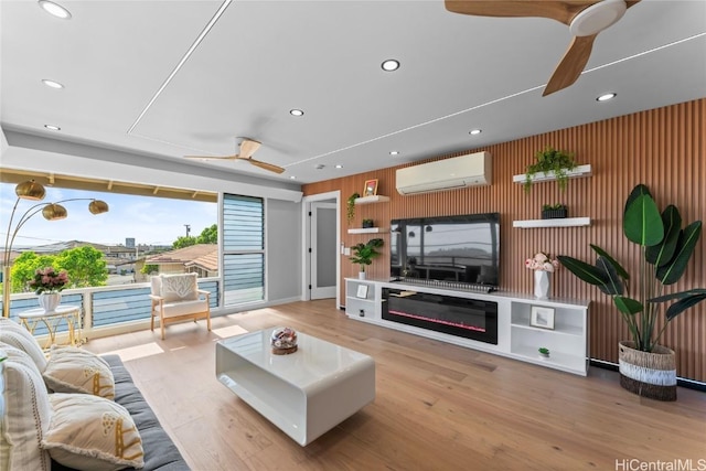 living room with light hardwood / wood-style flooring, an AC wall unit, and ceiling fan