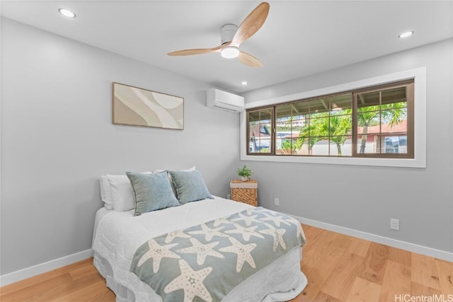 bedroom featuring hardwood / wood-style floors, a wall mounted air conditioner, and ceiling fan