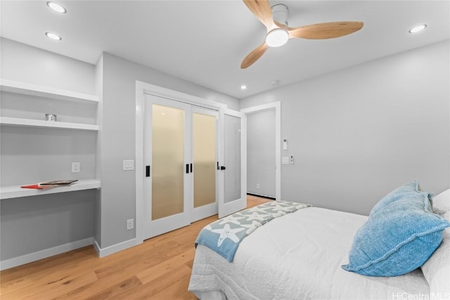 bedroom featuring light wood-type flooring, built in desk, ceiling fan, and french doors