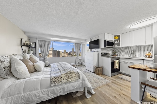 bedroom with sink, light hardwood / wood-style flooring, and a textured ceiling