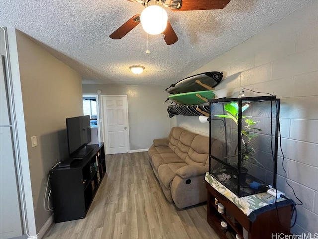 living room with wood-type flooring, ceiling fan, and a textured ceiling