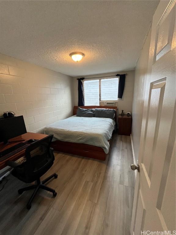 bedroom with hardwood / wood-style flooring and a textured ceiling