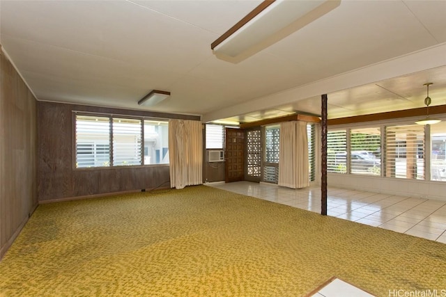 empty room featuring carpet flooring, wooden walls, plenty of natural light, and cooling unit