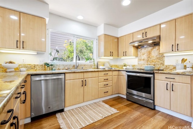 kitchen with stainless steel appliances, light brown cabinetry, sink, and light hardwood / wood-style flooring