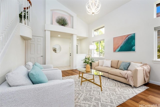 living room with an inviting chandelier, wood-type flooring, and high vaulted ceiling