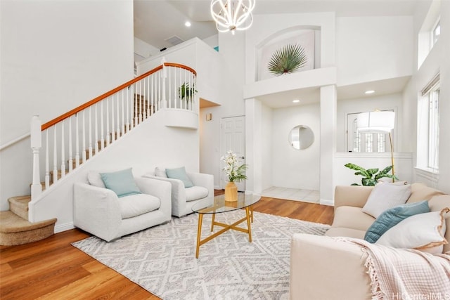 living room with wood-type flooring, a towering ceiling, and a chandelier