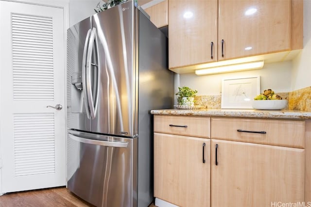 kitchen with light stone counters, stainless steel fridge with ice dispenser, dark hardwood / wood-style floors, and light brown cabinets