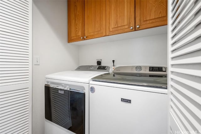 clothes washing area with cabinets and washer and dryer