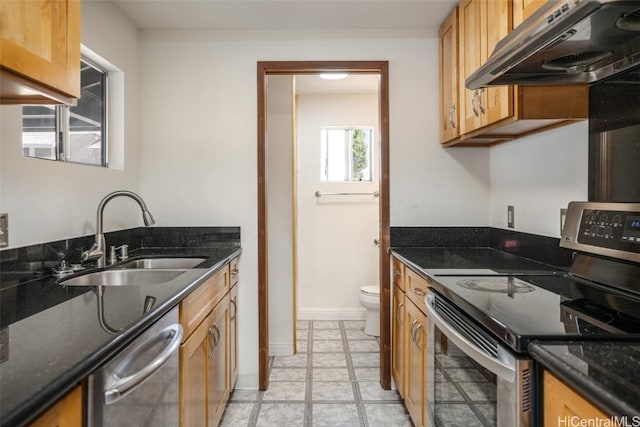 kitchen with dark stone countertops, sink, range hood, and appliances with stainless steel finishes