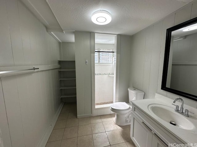 bathroom with tile patterned flooring, vanity, a textured ceiling, and toilet