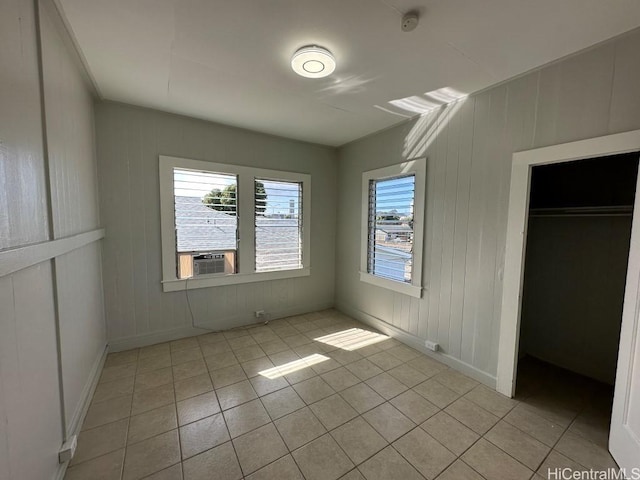 unfurnished bedroom featuring cooling unit, multiple windows, a closet, and light tile patterned floors