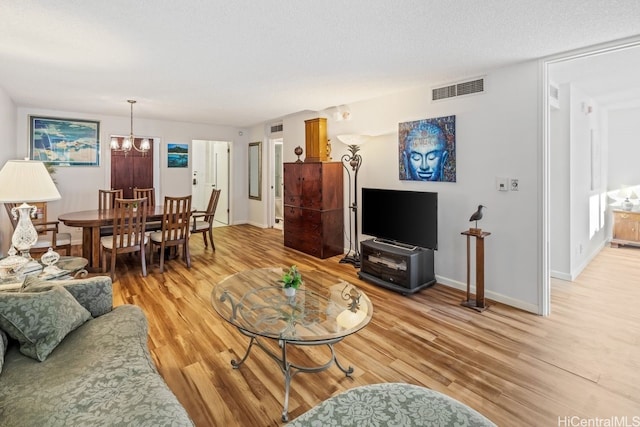 living room featuring a chandelier, a textured ceiling, and light wood-type flooring