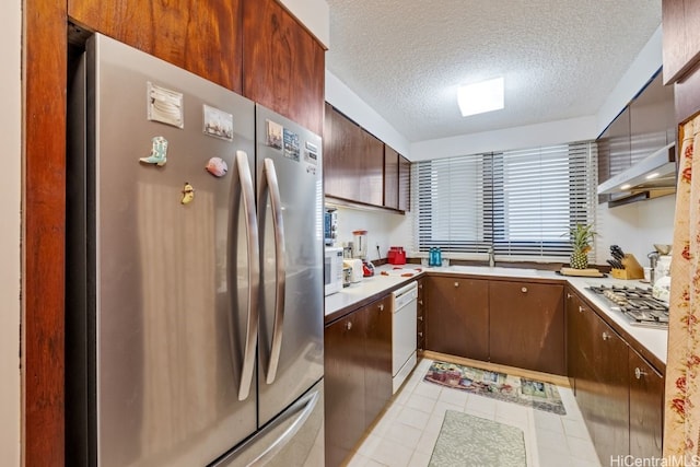 kitchen with sink, a textured ceiling, stainless steel appliances, and wall chimney exhaust hood