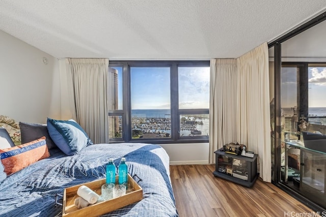 bedroom featuring multiple windows, hardwood / wood-style floors, and a textured ceiling