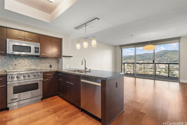 kitchen with appliances with stainless steel finishes, decorative light fixtures, a mountain view, and kitchen peninsula