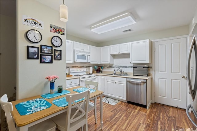 kitchen featuring sink, decorative light fixtures, dark hardwood / wood-style flooring, white appliances, and white cabinets