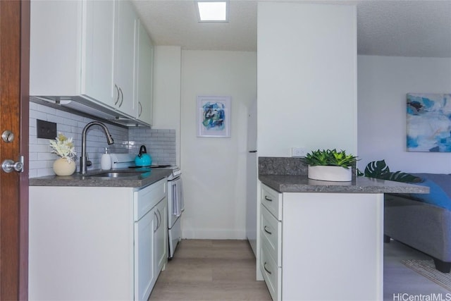 kitchen featuring sink, kitchen peninsula, white cabinets, and backsplash