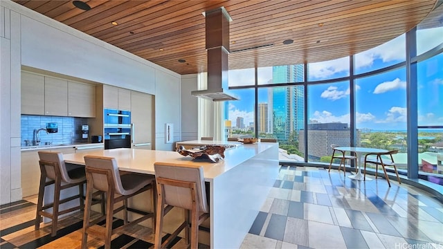 kitchen featuring expansive windows, island range hood, backsplash, and wood ceiling