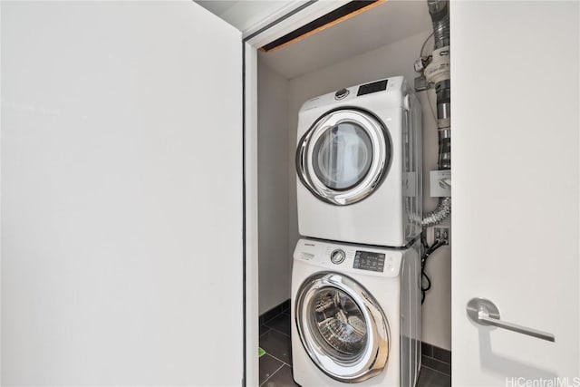 laundry room featuring stacked washer and dryer and tile patterned flooring