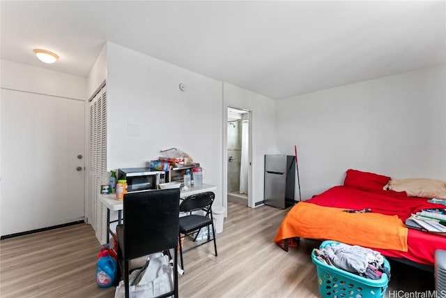 bedroom featuring stainless steel refrigerator, a closet, and light wood-type flooring