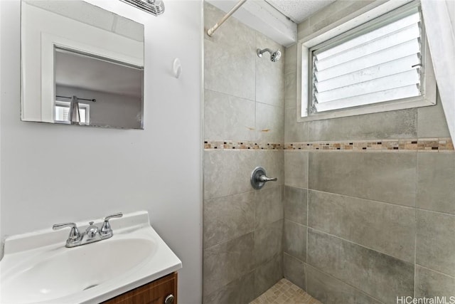 bathroom with vanity, a tile shower, and a wealth of natural light