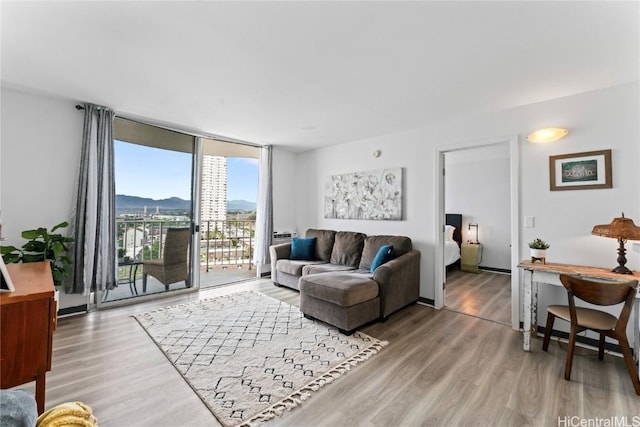 living room with expansive windows, a mountain view, and hardwood / wood-style flooring