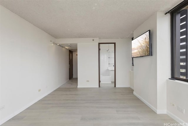 unfurnished room with light hardwood / wood-style flooring and a textured ceiling