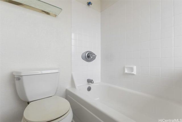 bathroom featuring tiled shower / bath combo and toilet