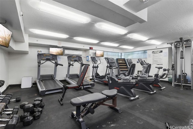 exercise room with a textured ceiling and an AC wall unit