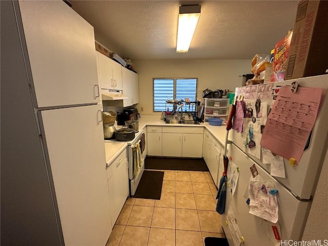 kitchen with sink, white cabinetry, a textured ceiling, light tile patterned floors, and white appliances