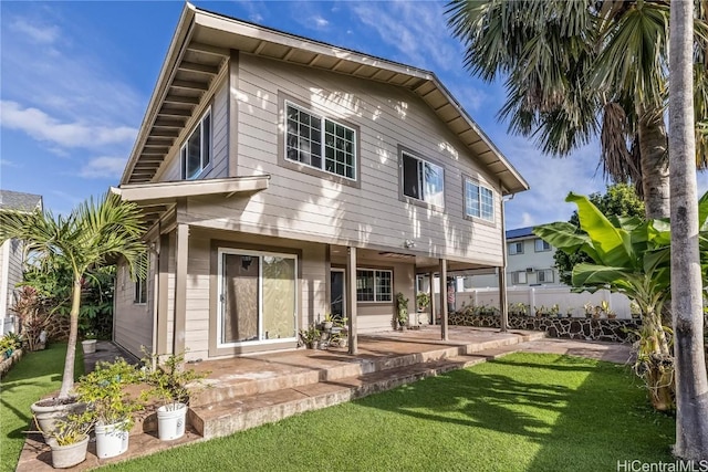 rear view of house with a patio, a lawn, and fence