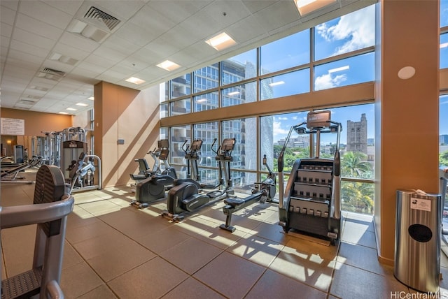 workout area featuring a wall of windows, a view of city, visible vents, and a drop ceiling