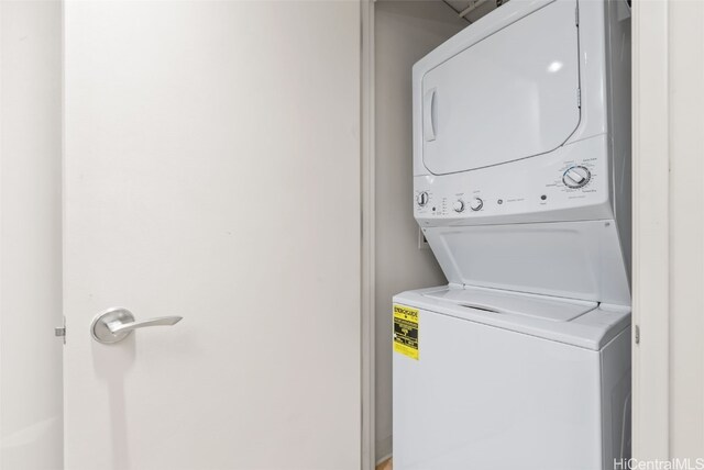 clothes washing area with stacked washing maching and dryer