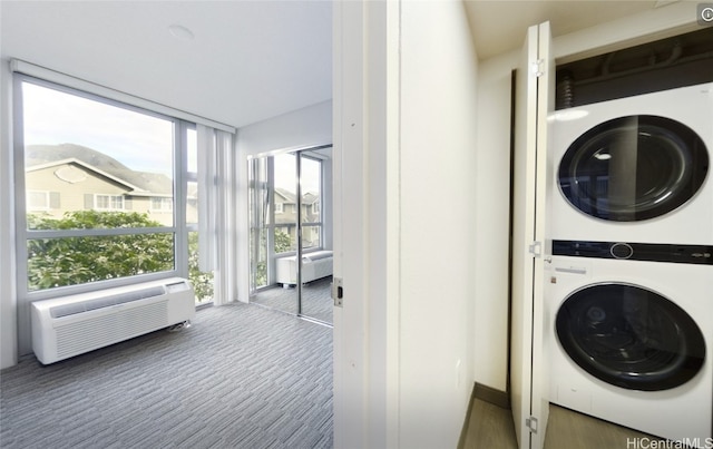 clothes washing area with stacked washing maching and dryer, a wall mounted AC, and dark carpet