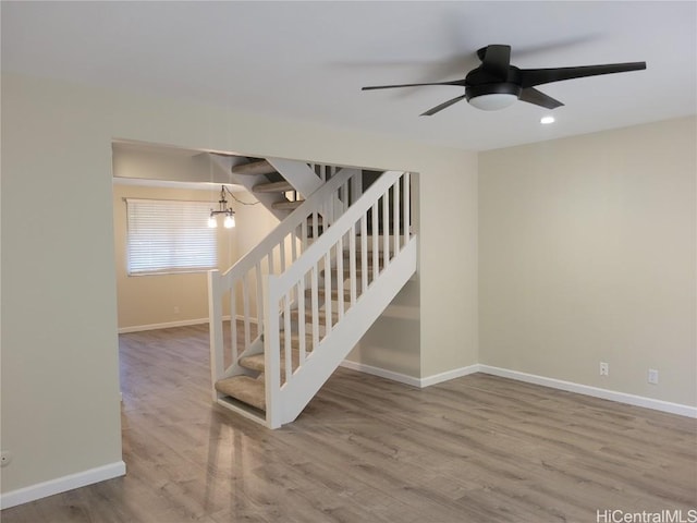 stairs featuring ceiling fan and hardwood / wood-style floors