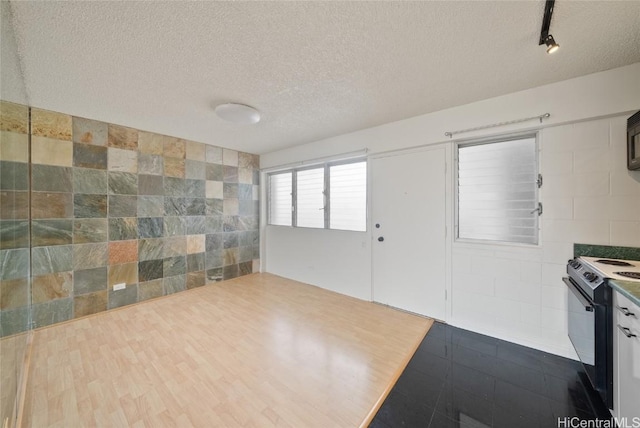 interior space featuring wood-type flooring, tile walls, track lighting, and a textured ceiling