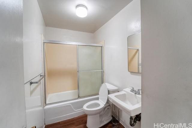 full bathroom featuring sink, hardwood / wood-style floors, shower / bath combination with glass door, and toilet