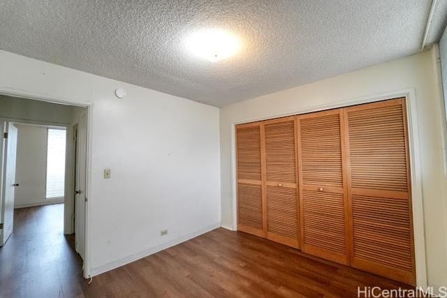 unfurnished bedroom featuring hardwood / wood-style flooring, a closet, and a textured ceiling