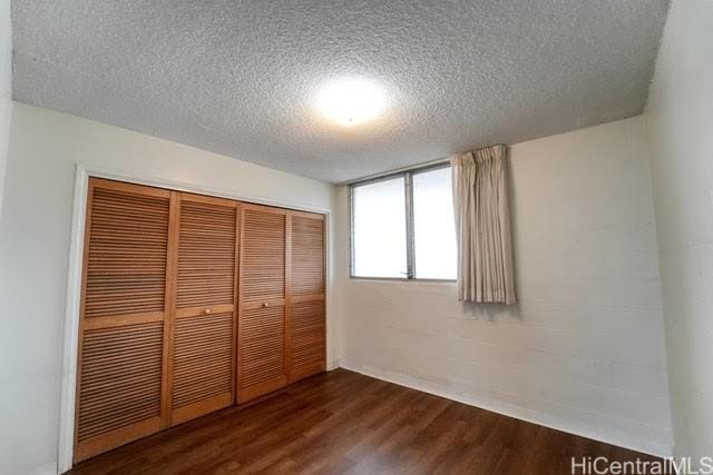 unfurnished bedroom with dark hardwood / wood-style floors, a textured ceiling, and a closet