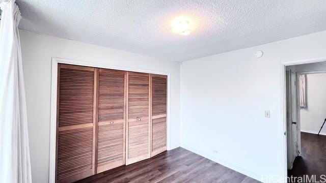 unfurnished bedroom with dark hardwood / wood-style flooring, a closet, and a textured ceiling